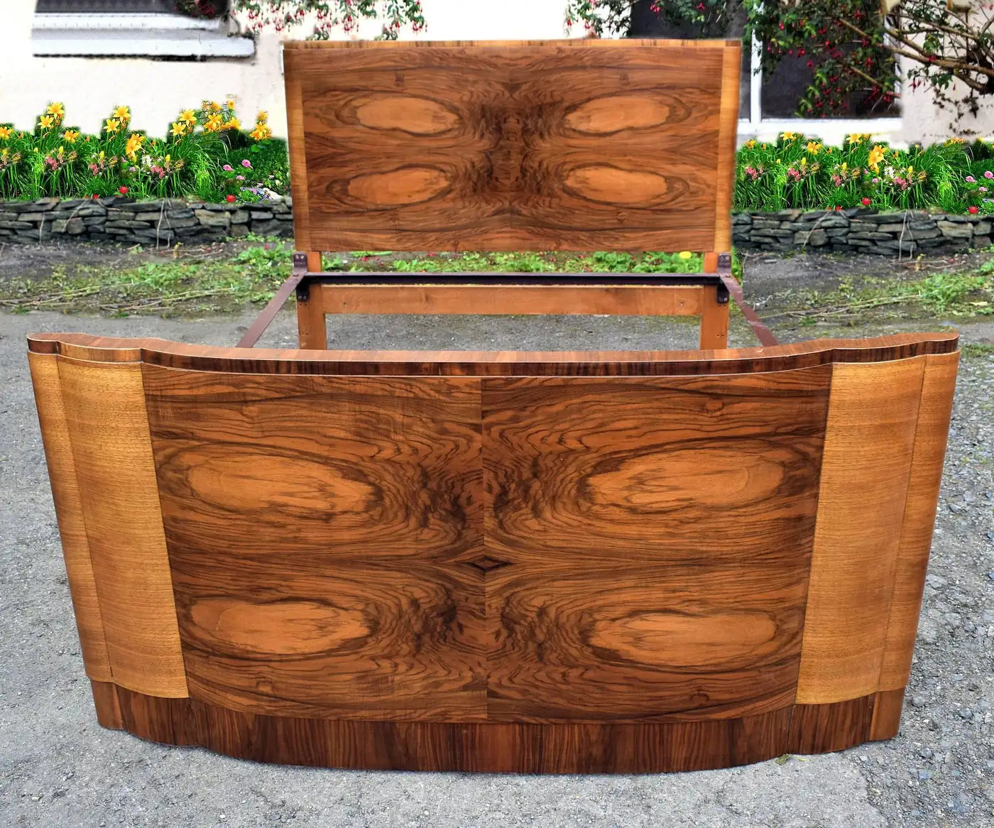 Wooden reception desk with a curved front and rectangular backrest on a gravel surface.