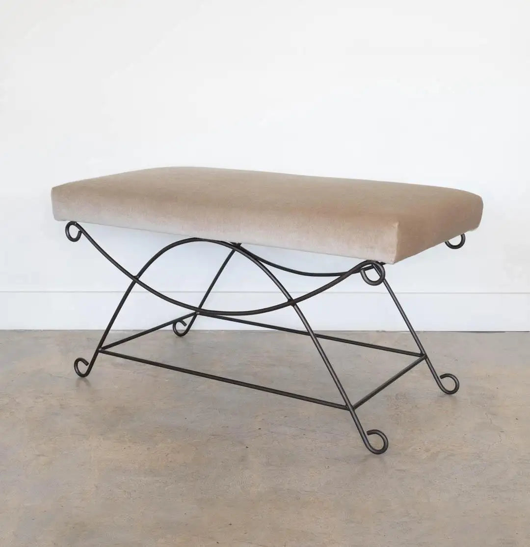 Beige ottoman with black metal frame on a light wooden floor.