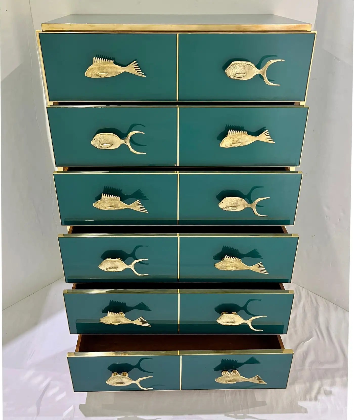 Teal dresser with gold fish-shaped handles on a white background