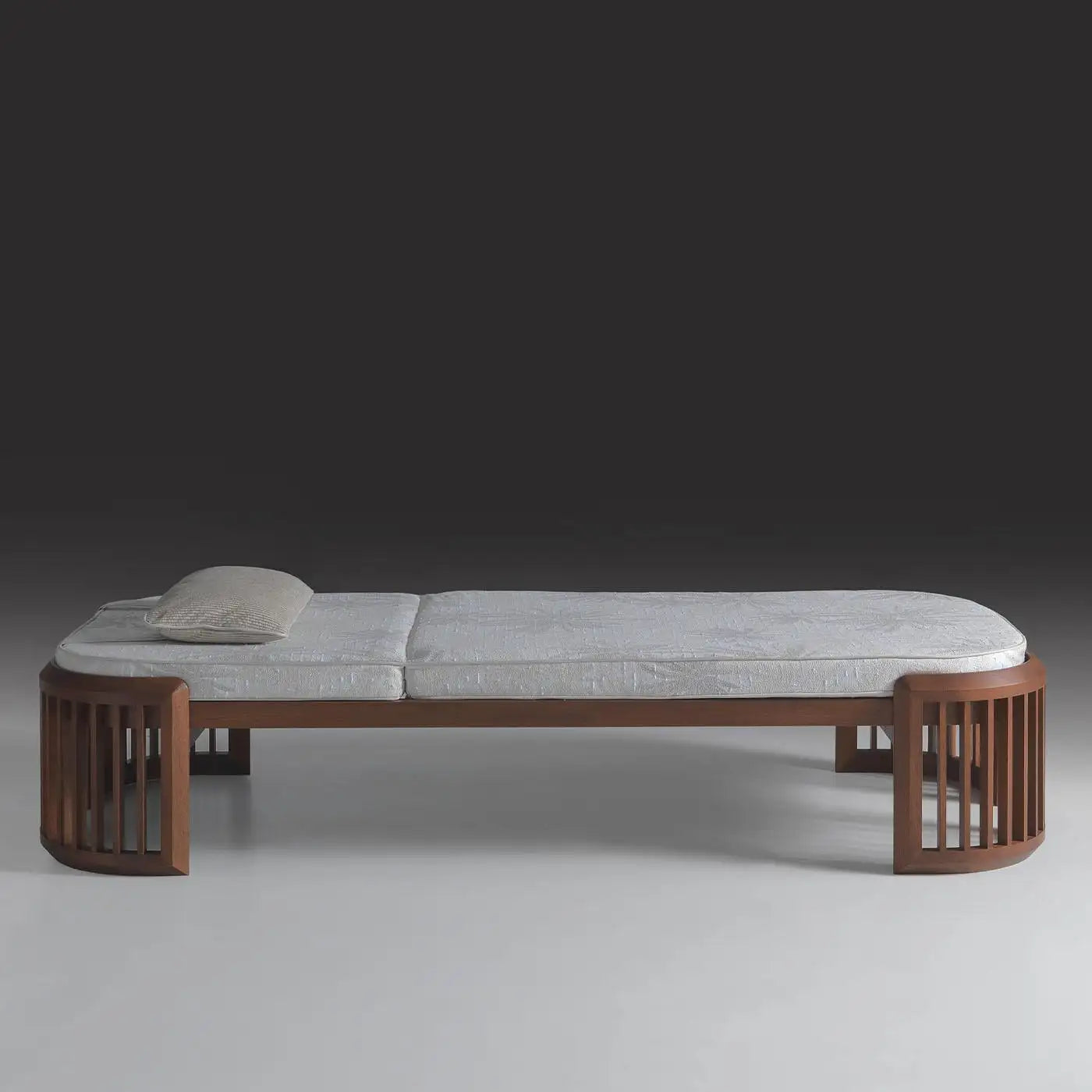 Wooden bed frame with gray mattress and pillow on a dark background