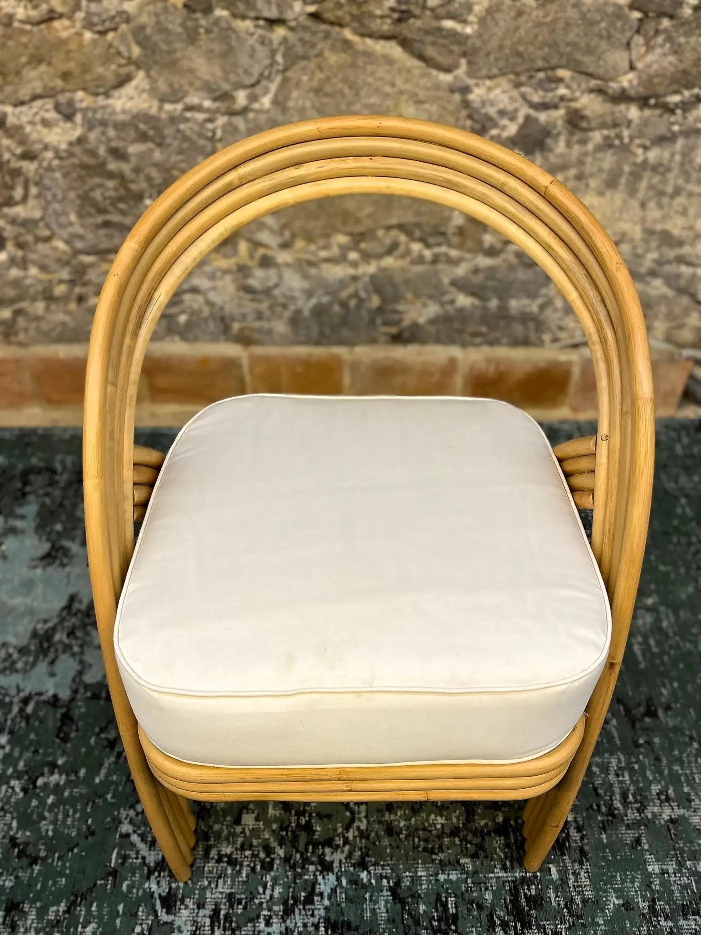Wicker chair with a white cushion on a textured floor and wall background