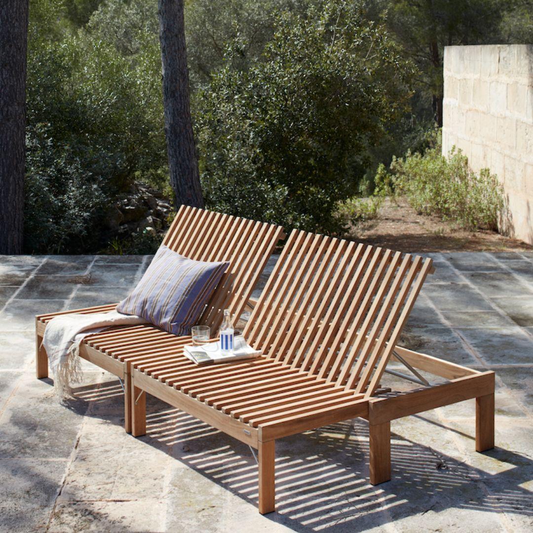 Wooden outdoor lounge chair with cushions on a stone patio