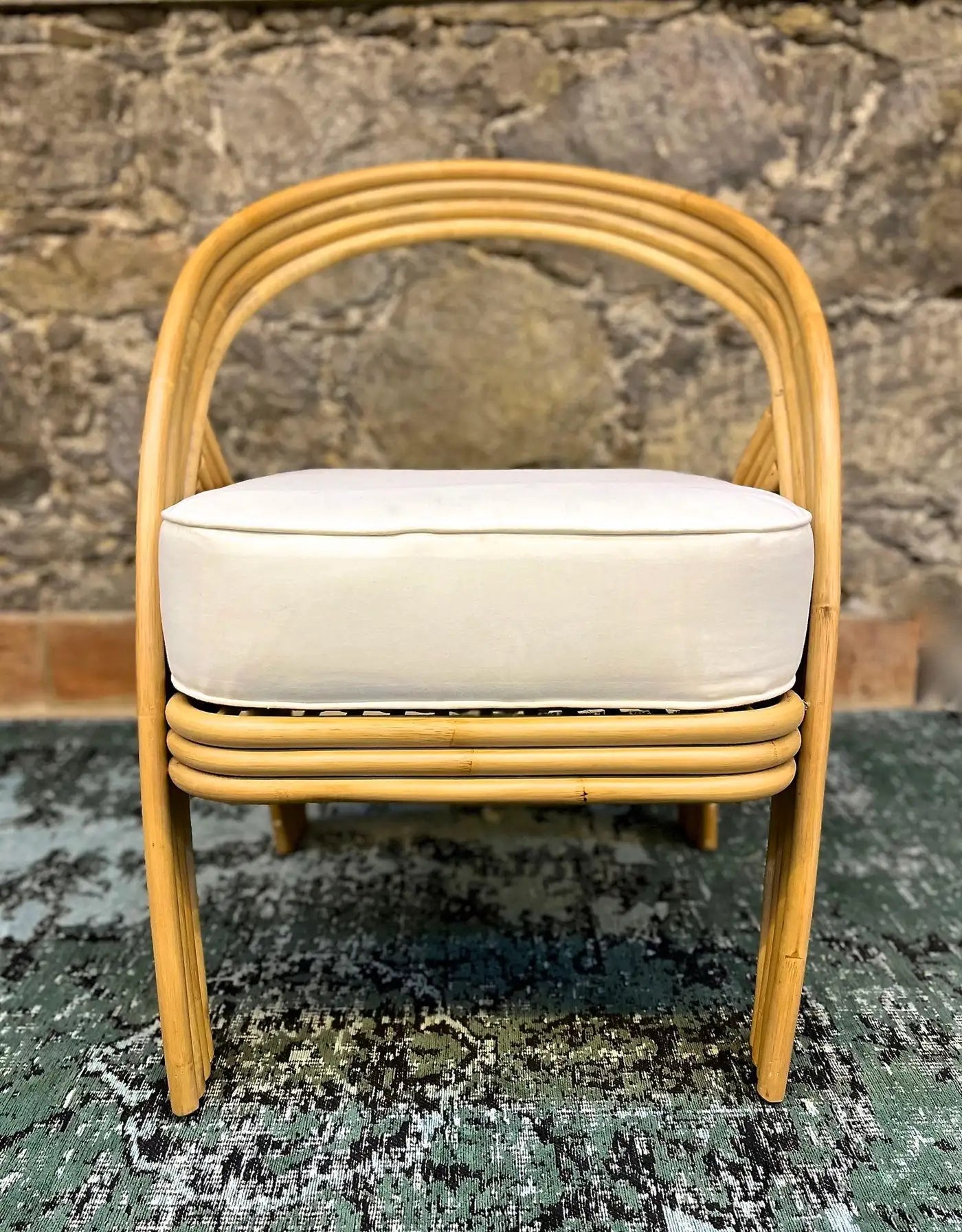 Beige chair with white cushion on a textured surface and stone wall background