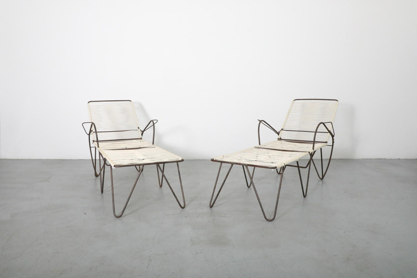 Pair of modern chairs with marble-like seats and metal frames on a plain floor.