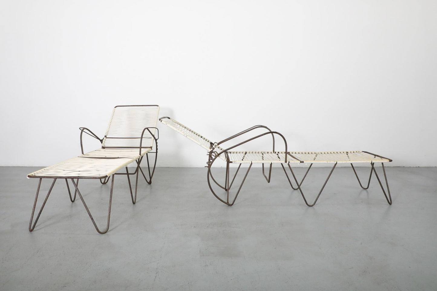 Modern outdoor furniture set with lounge chair and table on a gray floor.