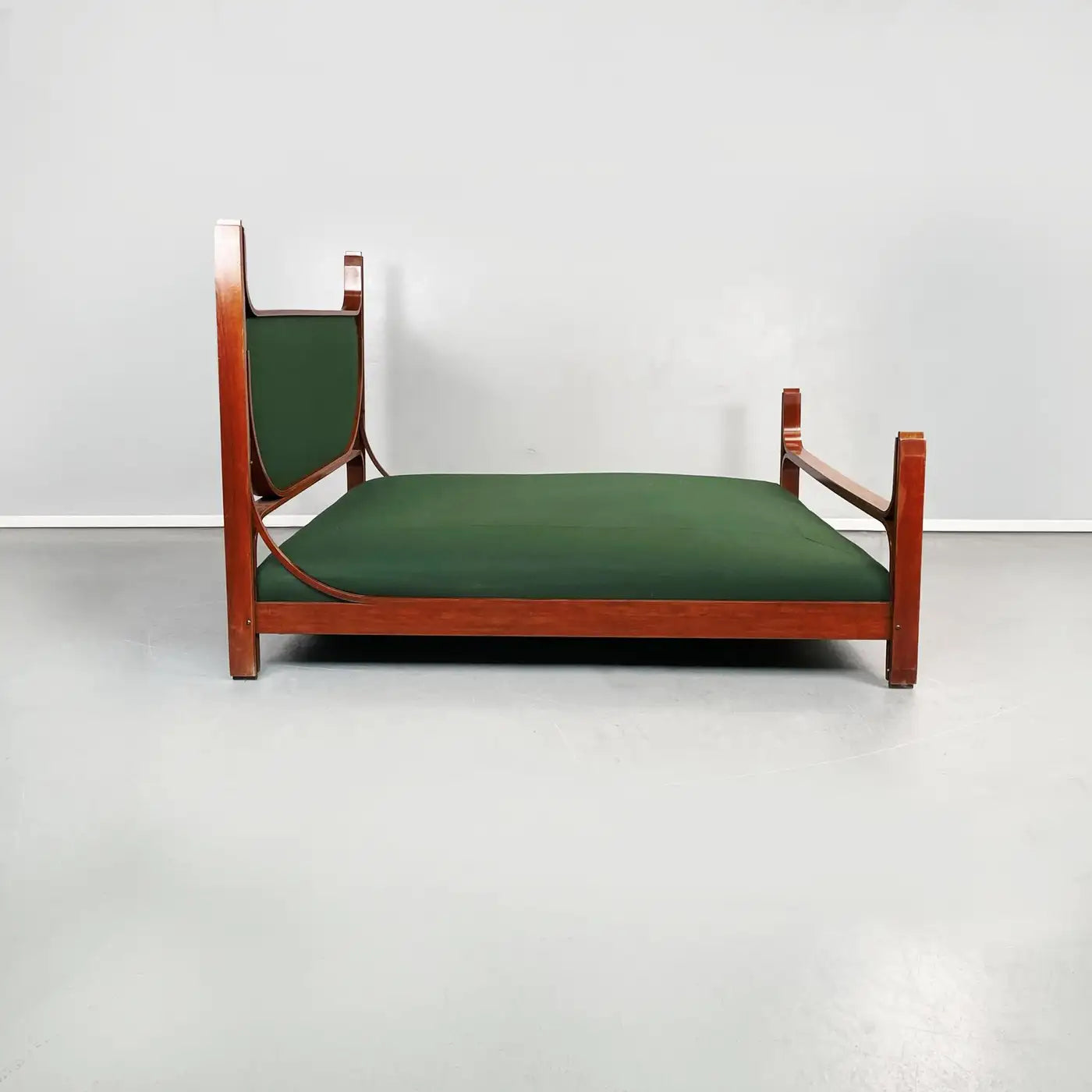 Wooden bed frame with green mattress against a white wall