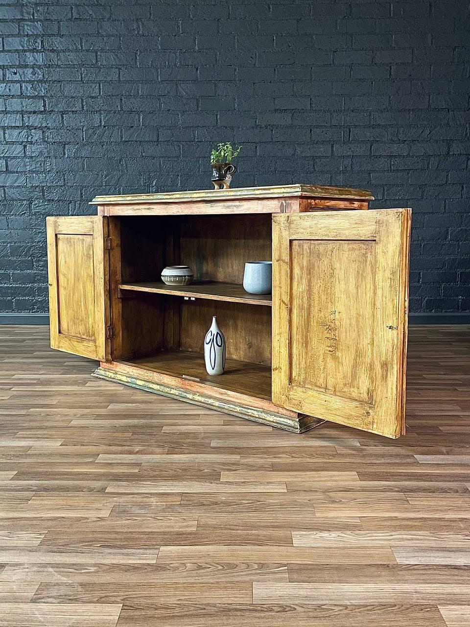 Wooden cabinet with open doors against a dark brick wall.