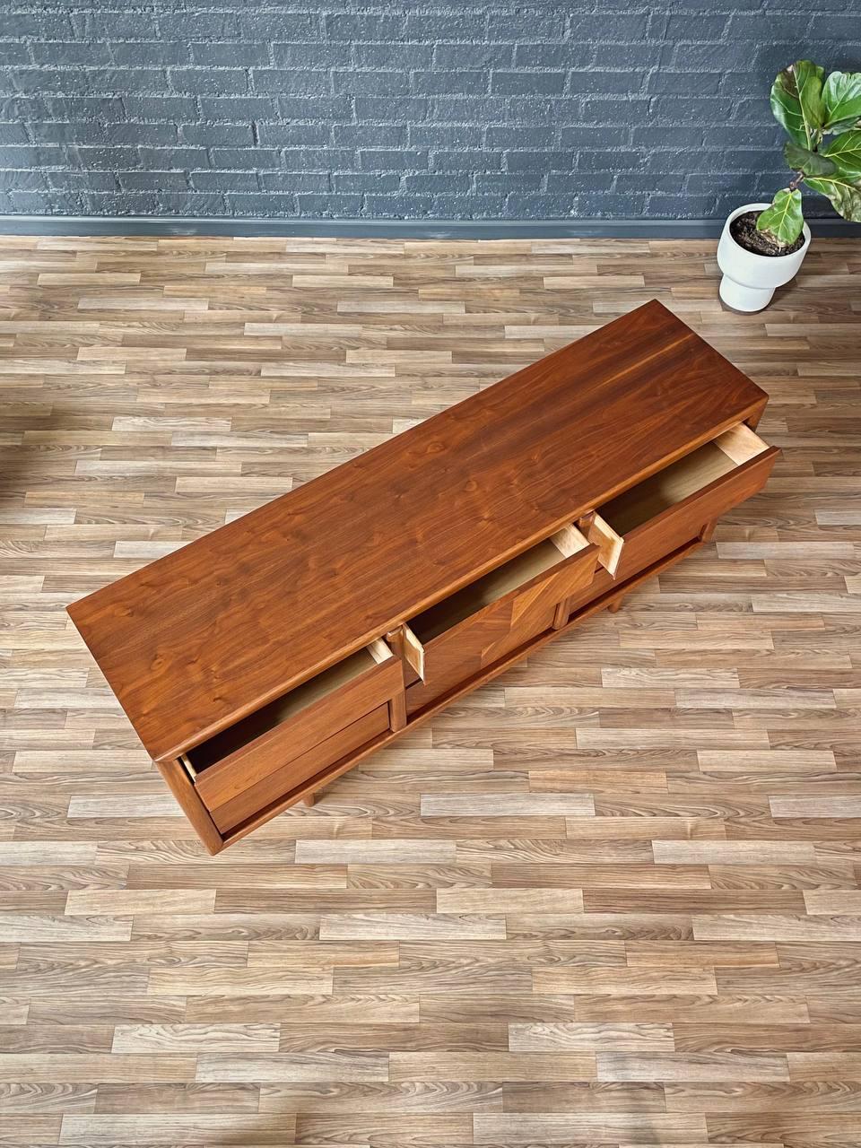 Wooden console table with drawers on a wooden floor against a brick wall.