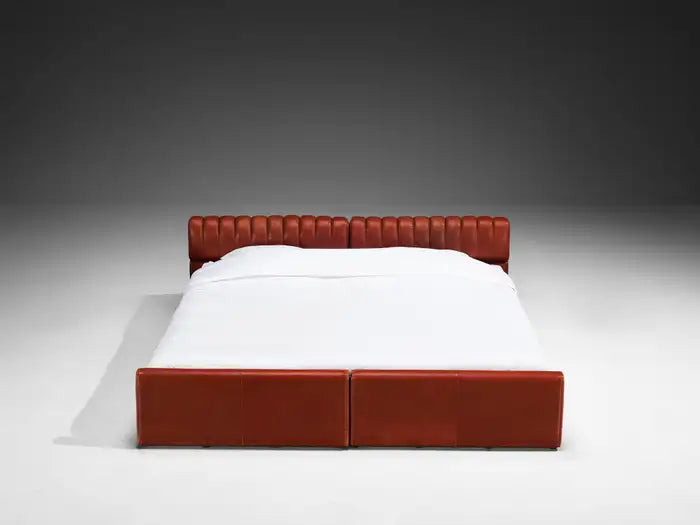 Red bed frame with white bedding on a gray background