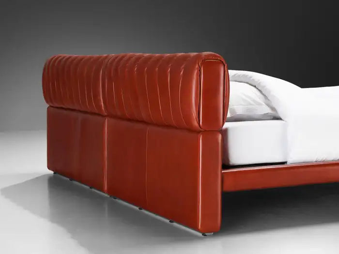 Red leather bed frame with white mattress on a gray background