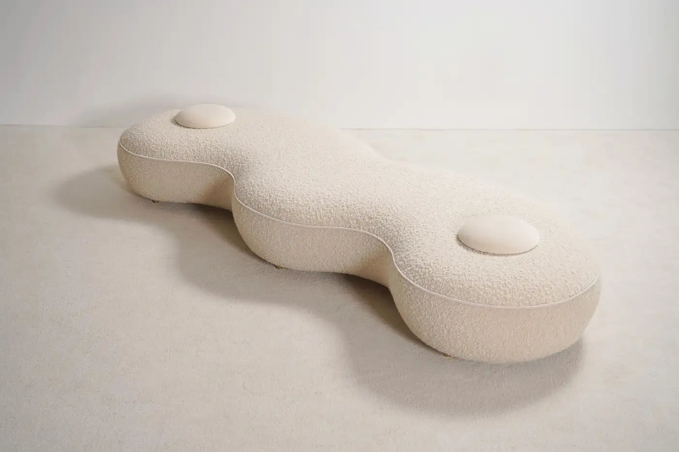 Sculptural white pillow with wavy design on a light gray background