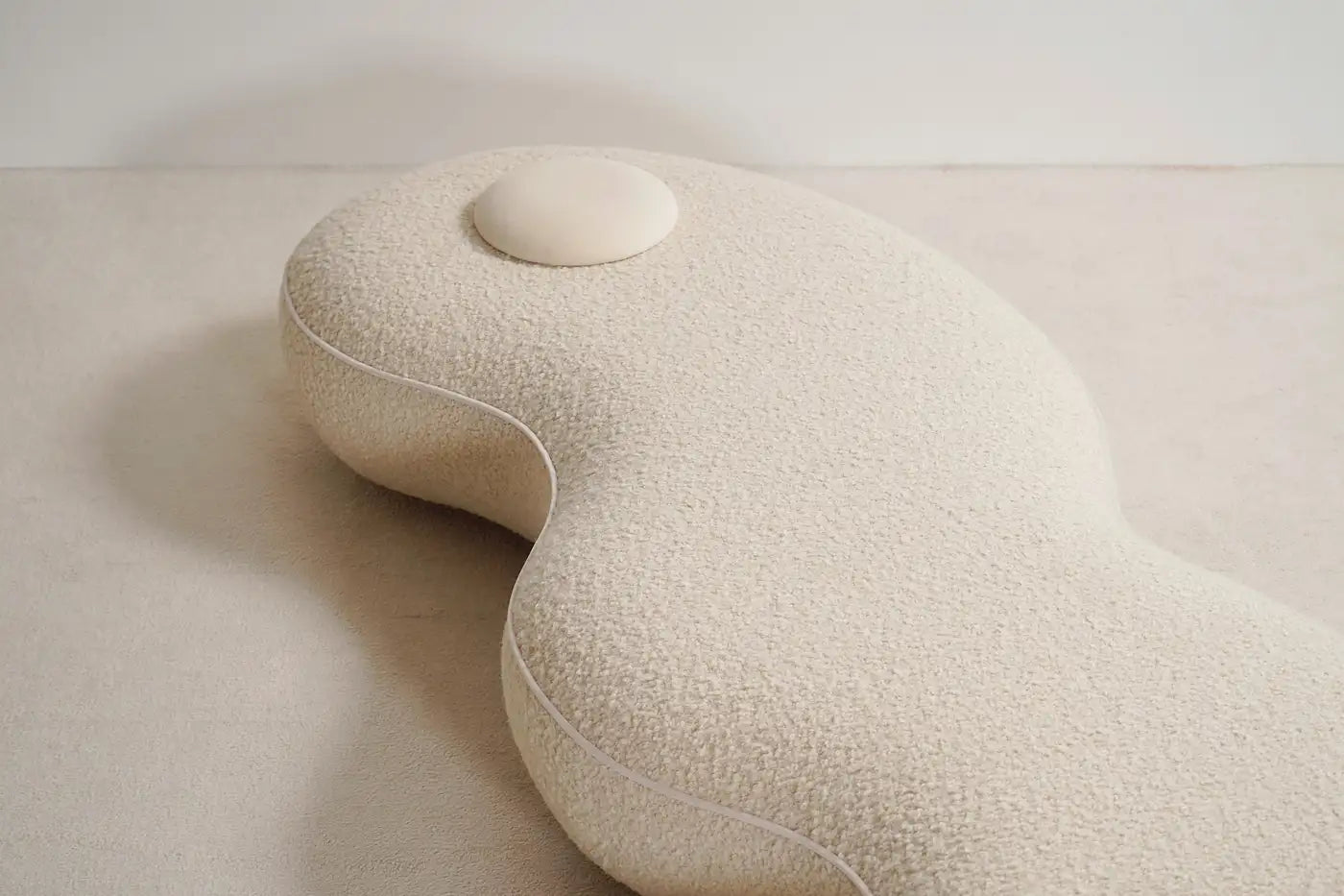 Beige U-shaped pillow on a light beige surface