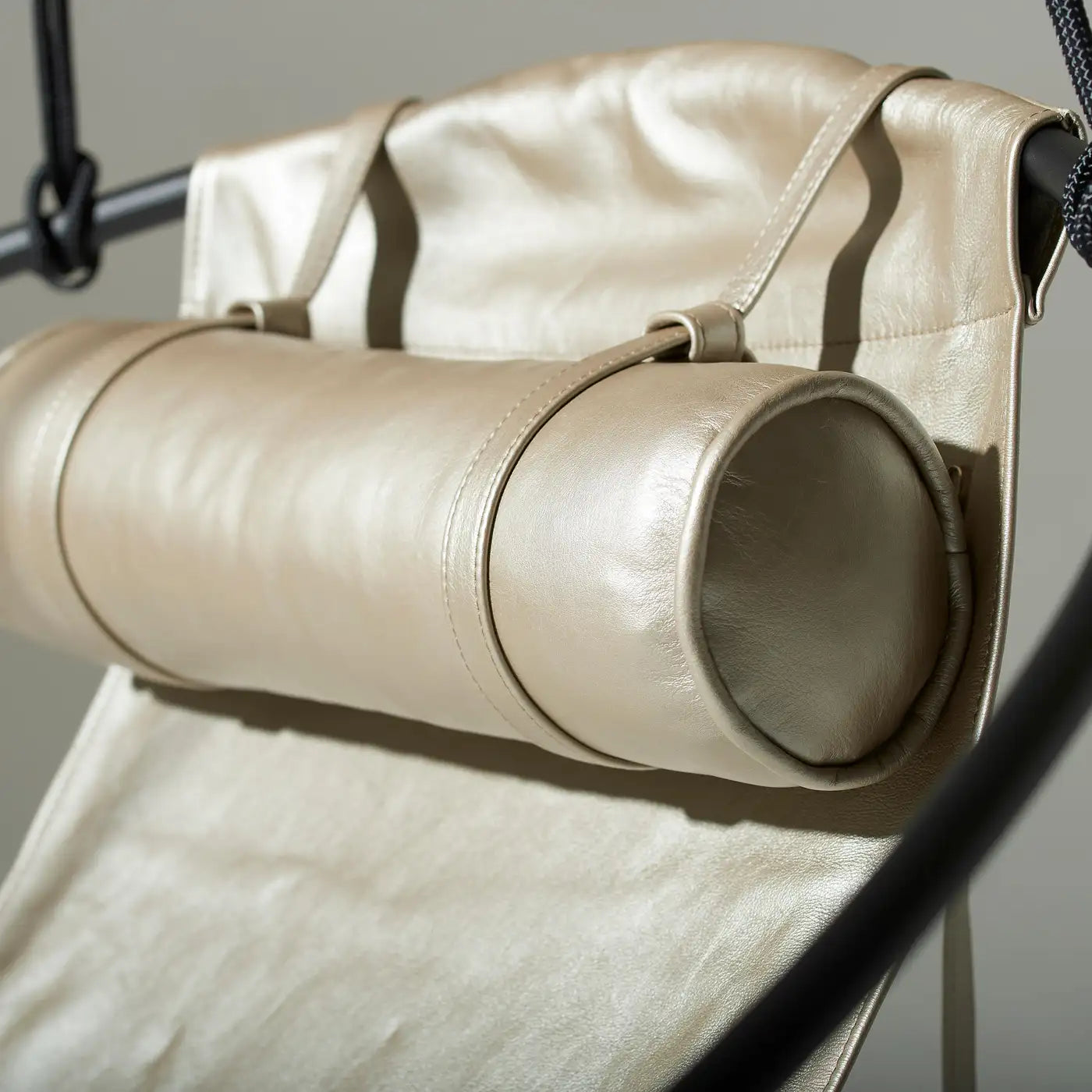 Close-up of a beige leather chair with a cylindrical armrest.