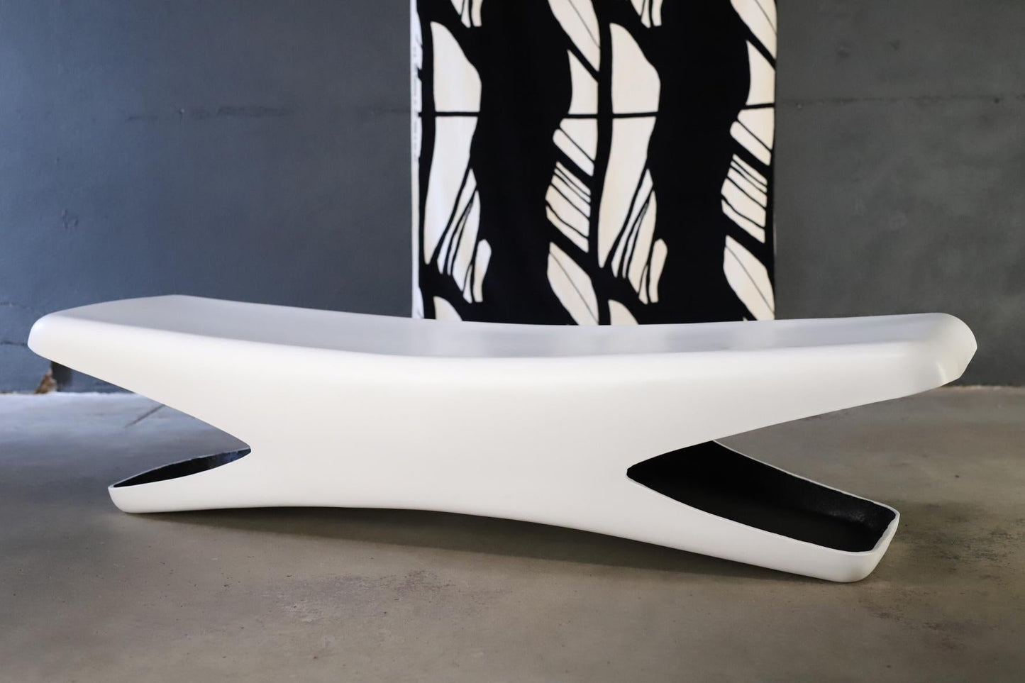 Modern white bench with a black and white patterned rug in the background