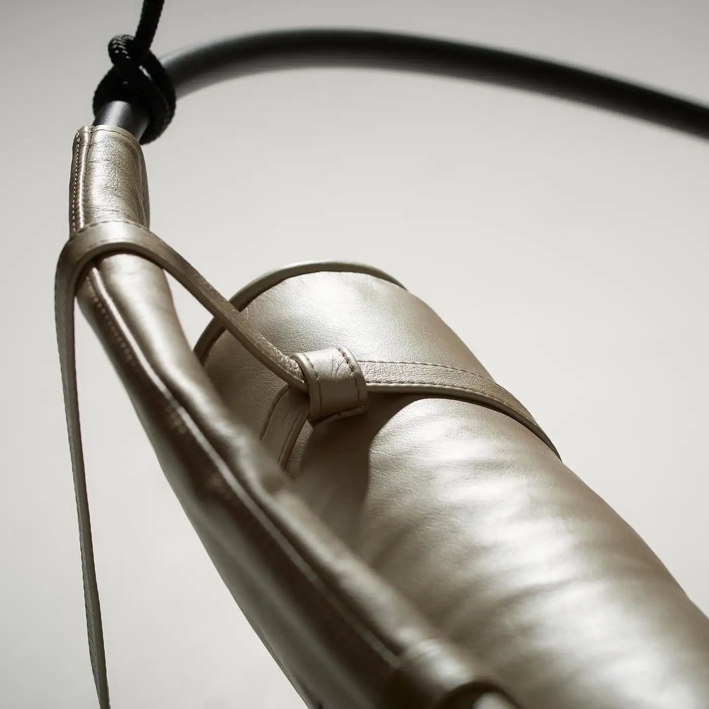 Close-up of a metallic object with a strap on a neutral background