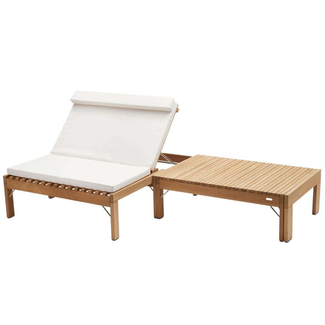 Wooden outdoor lounge chair with white cushion and matching ottoman on a white background