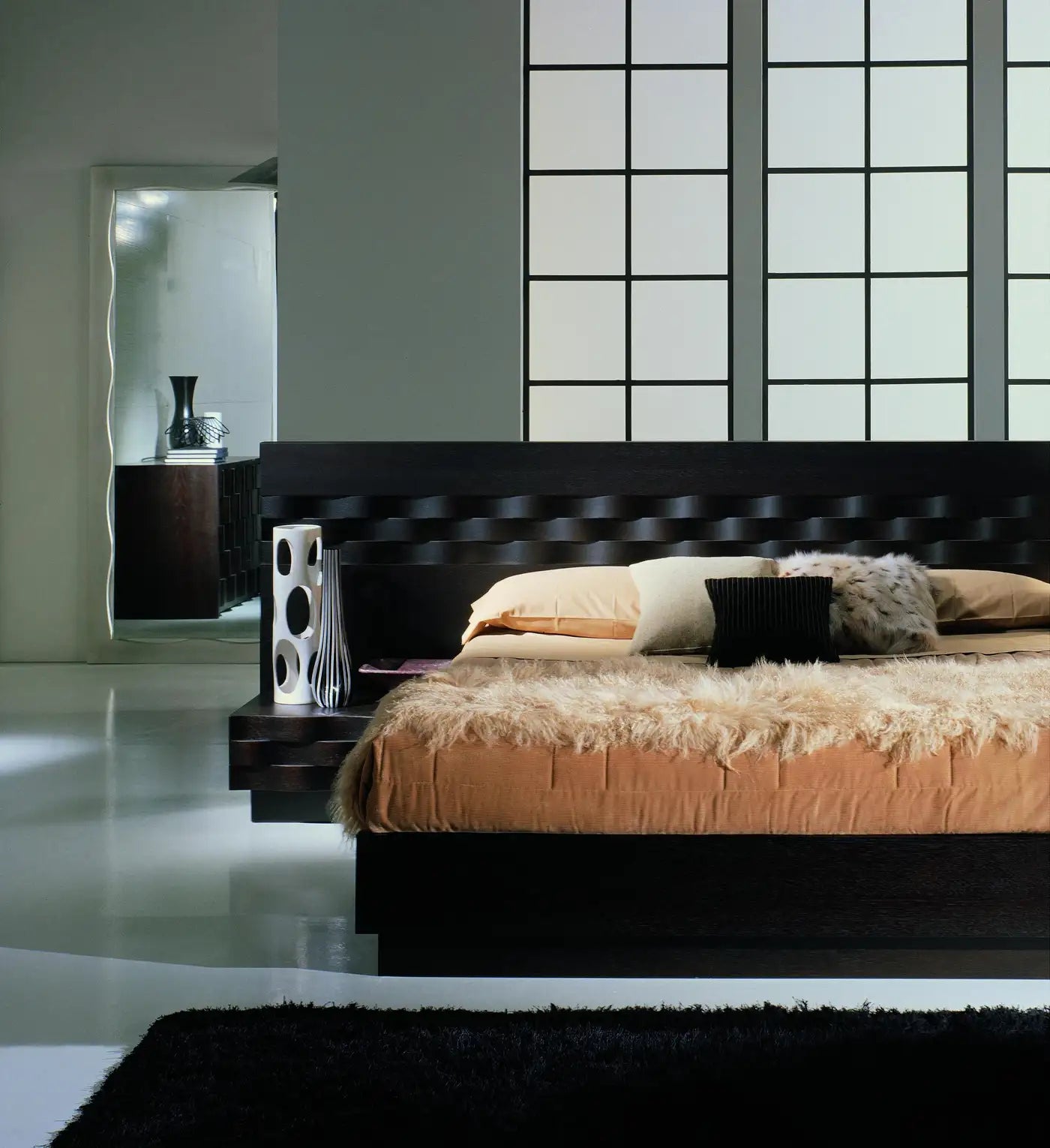 Modern bedroom with a dark wooden bed and decorative pillows.