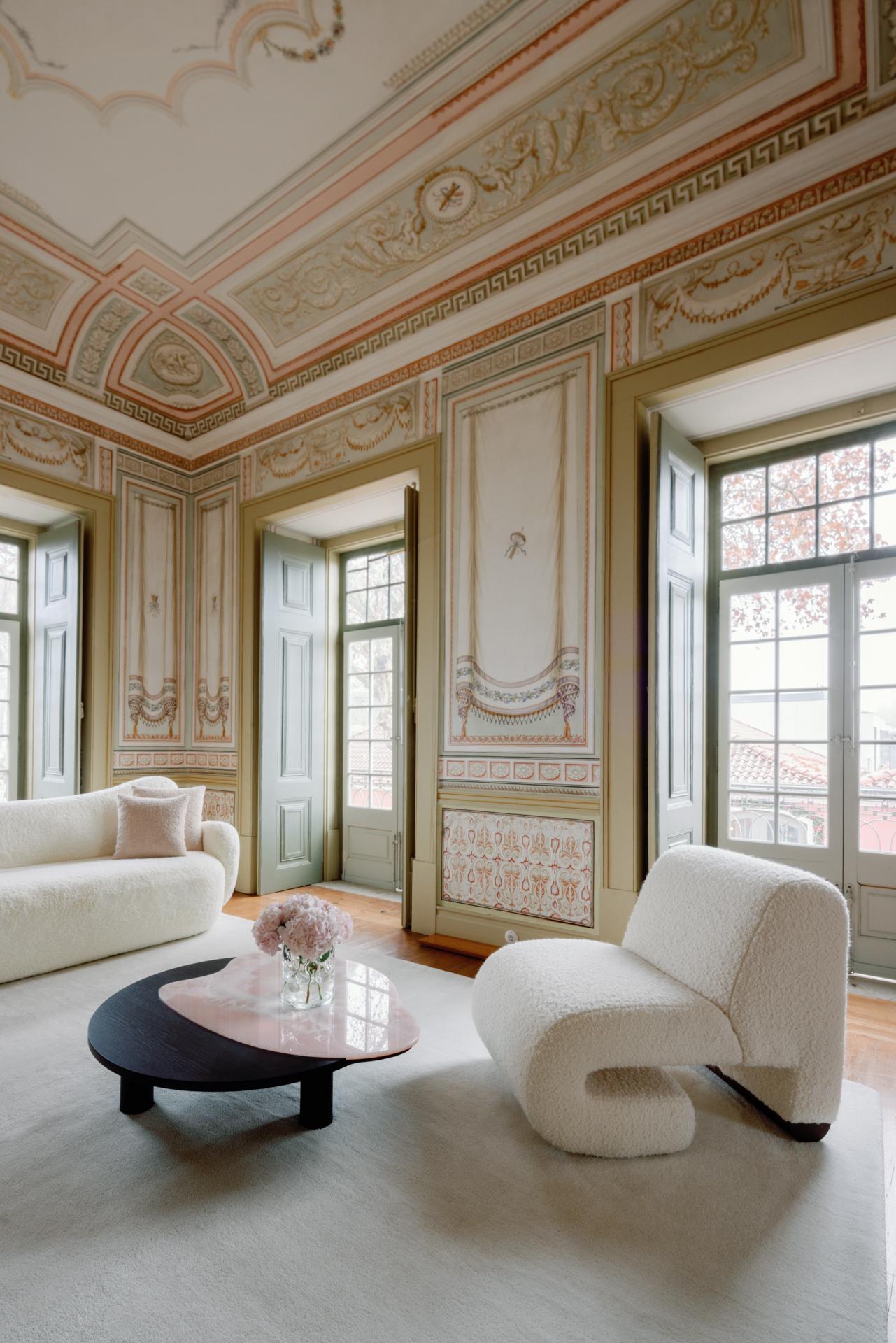 Luxurious living room with ornate ceiling and walls, featuring a white sofa and chair.