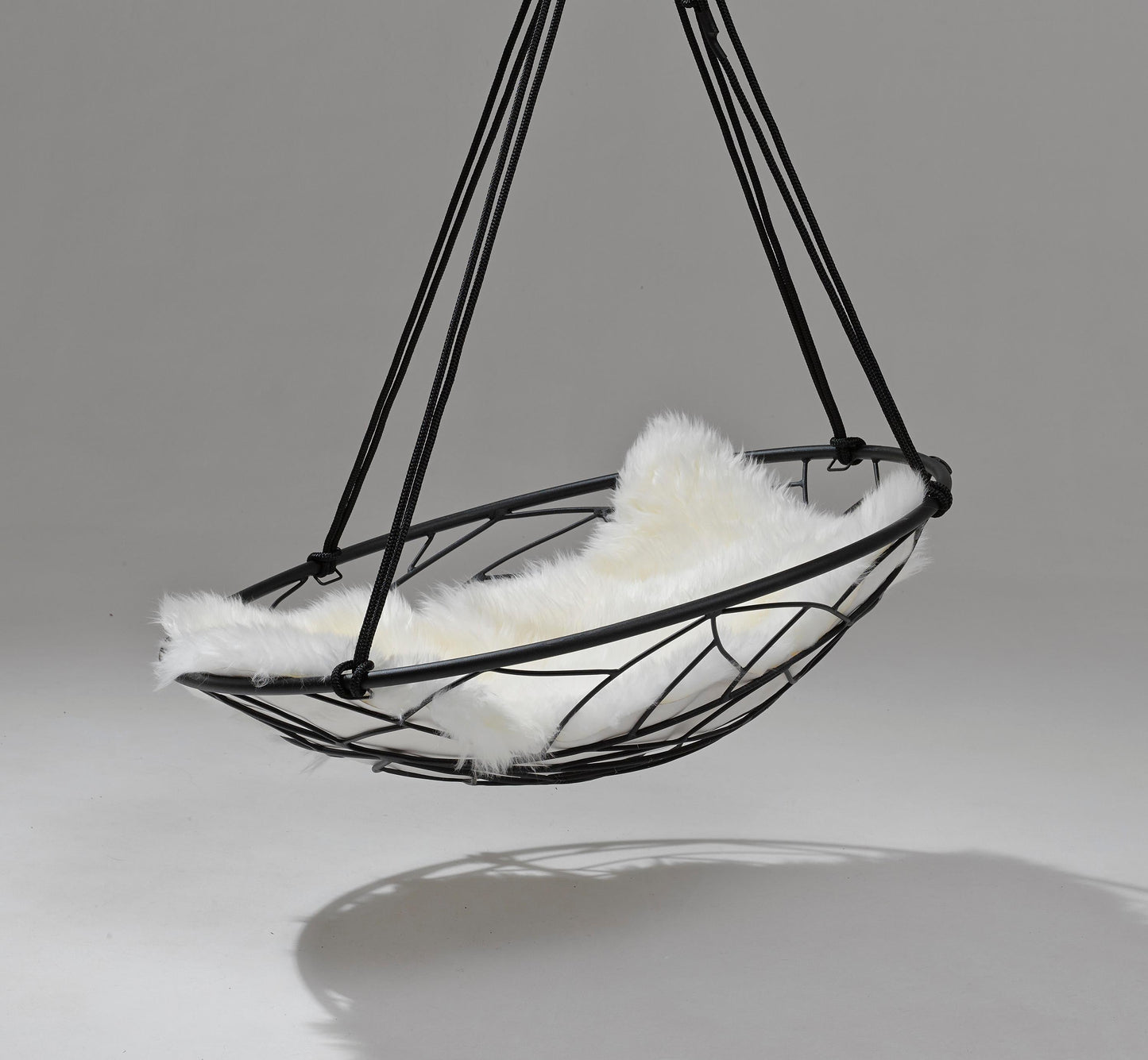 Hanging chair with white cushion and black metal frame on a gray background