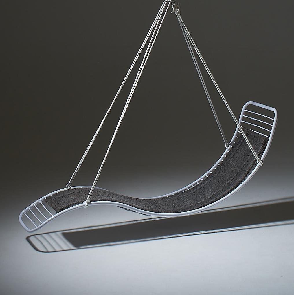 Modern hammock chair with gray cushion and metal frame on a dark background
