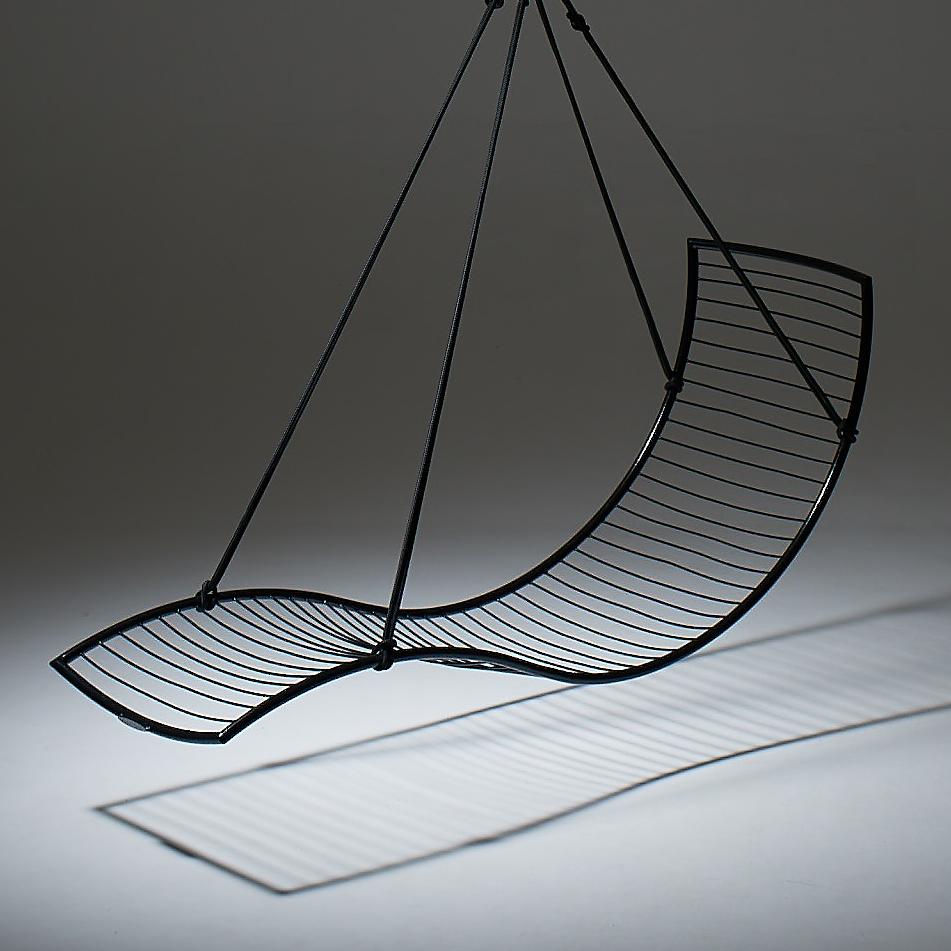 Black wire chair with curved design on a gray background