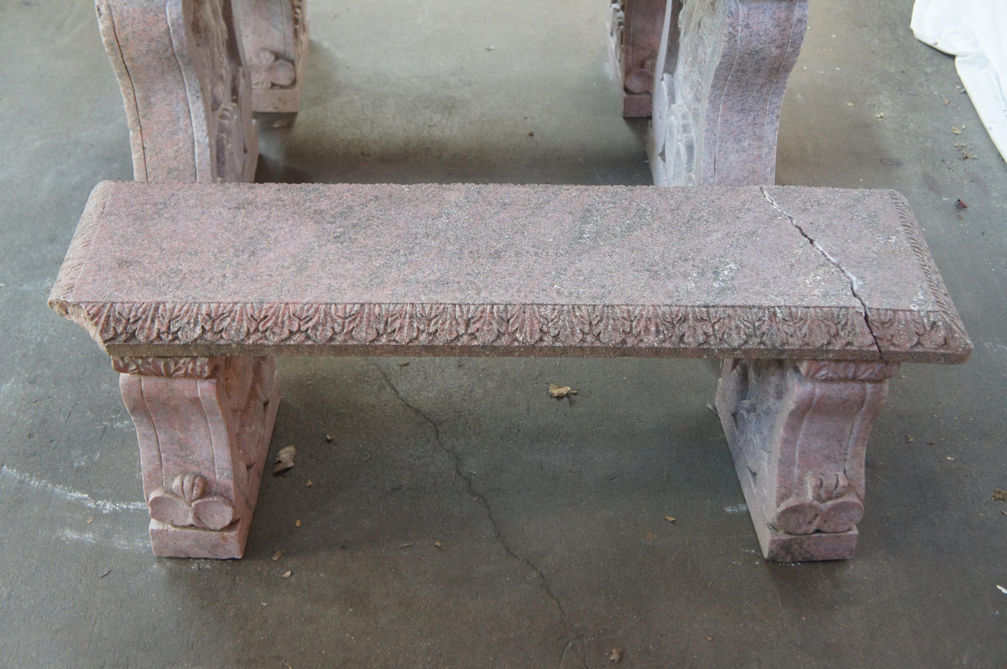 Pink stone bench with intricate carvings on a concrete floor