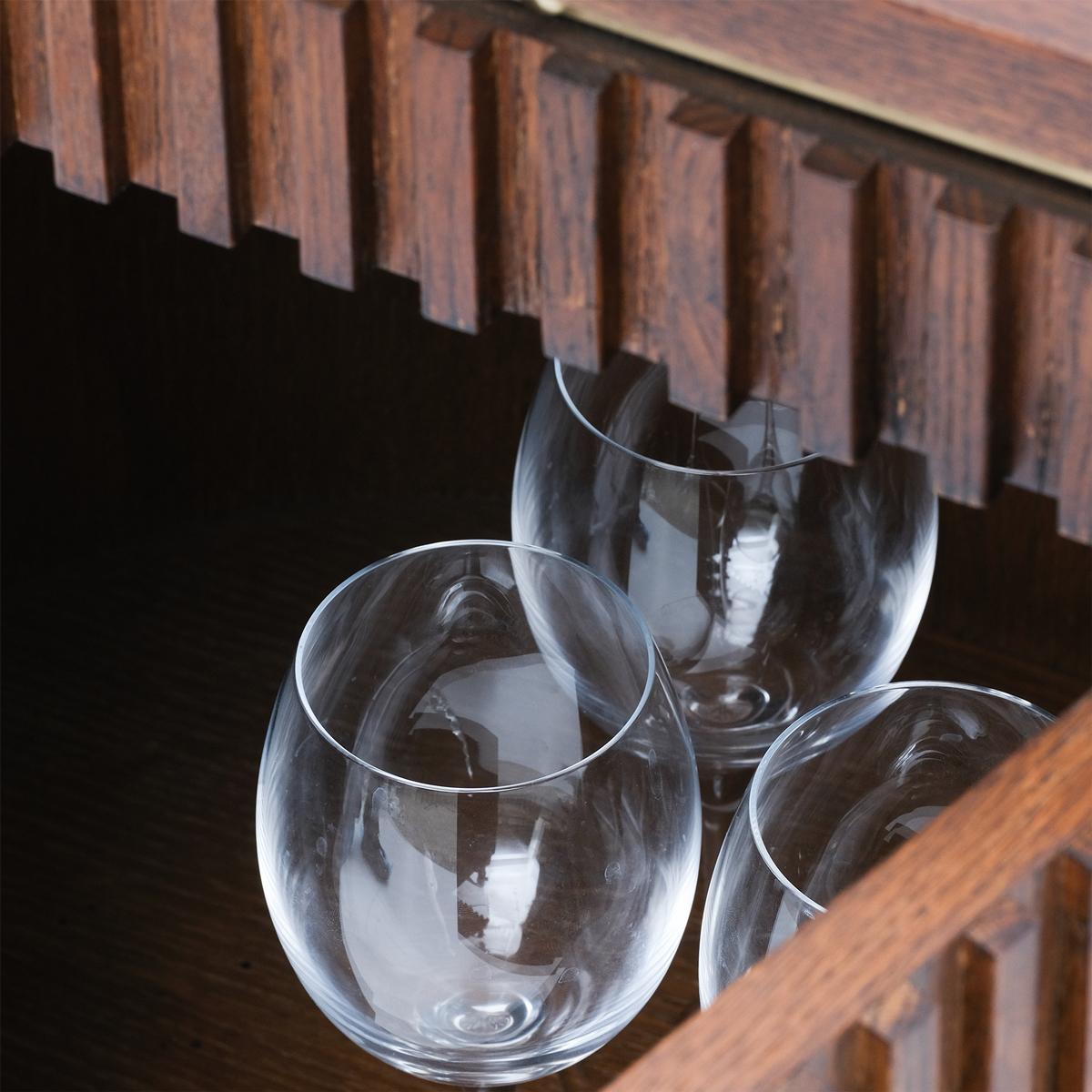 Three clear wine glasses on a wooden shelf