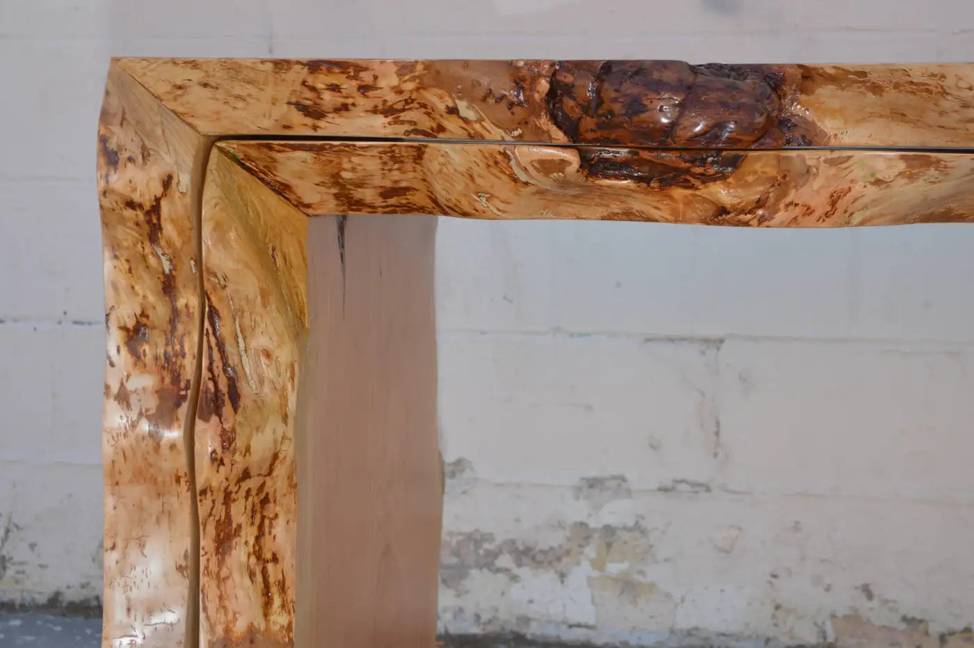 Wooden console table with a natural, textured finish against a white wall.