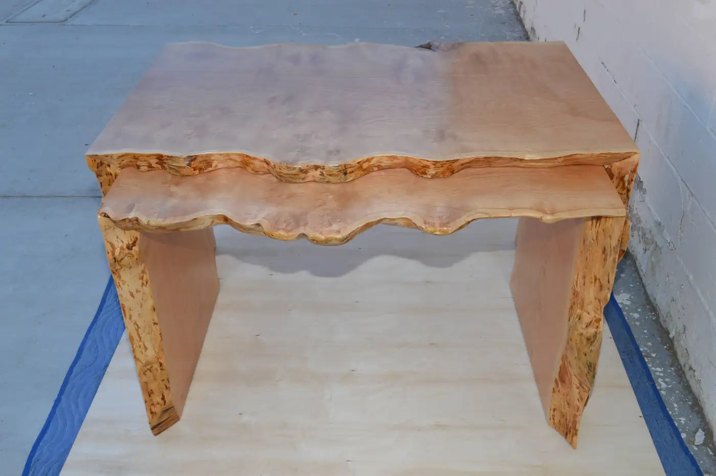 Wooden table with a natural edge design on a blue floor.