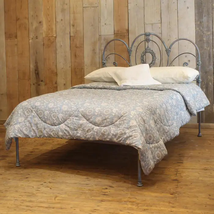 Bed with decorative headboard and bedding against a wooden wall.