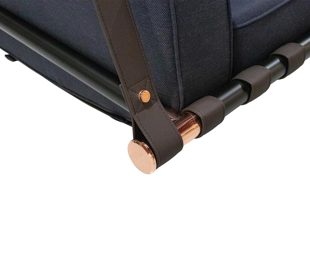 Close-up of a navy bag with brown straps and rose gold hardware on a white background