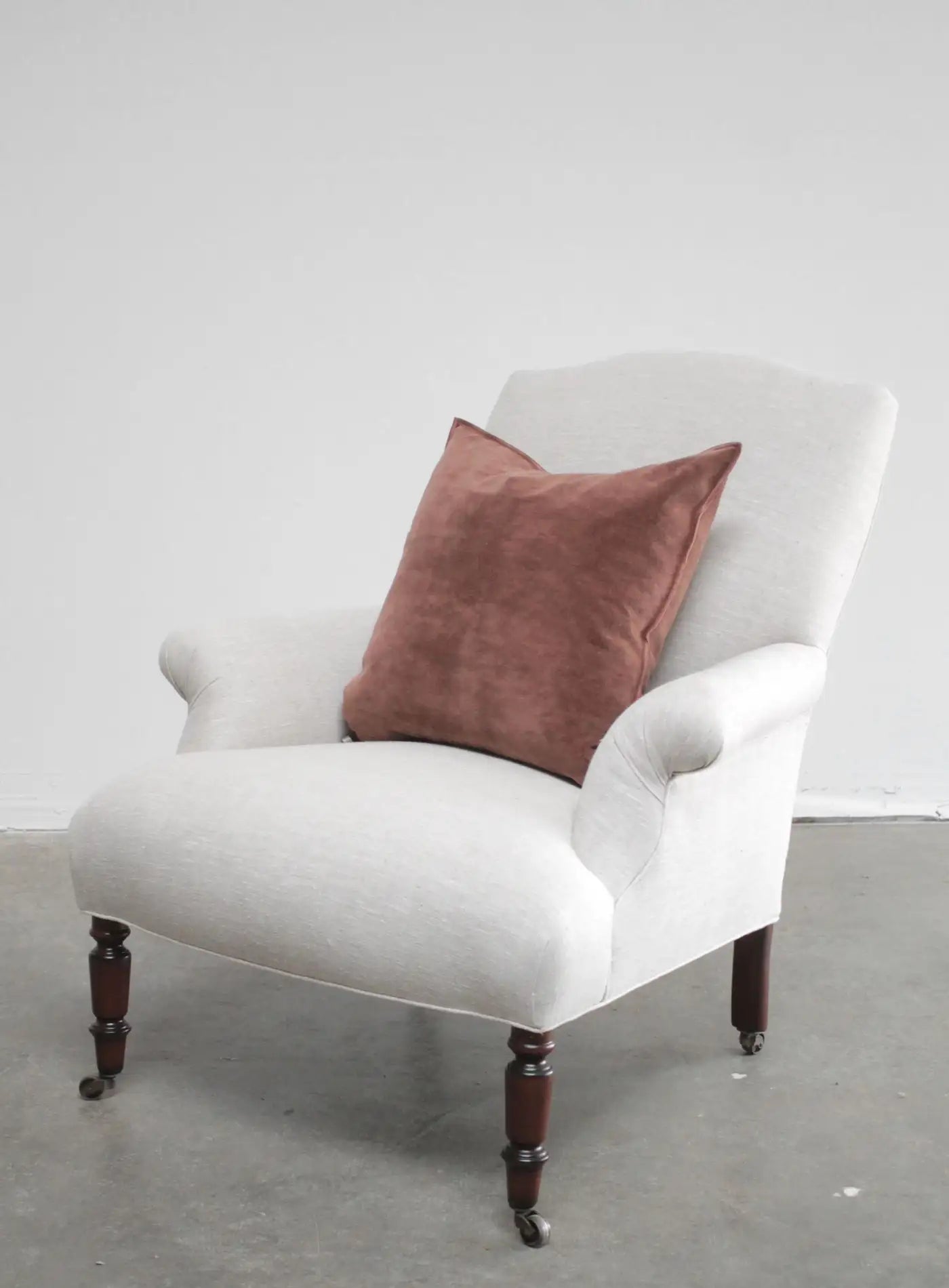 White armchair with a brown cushion on a plain background