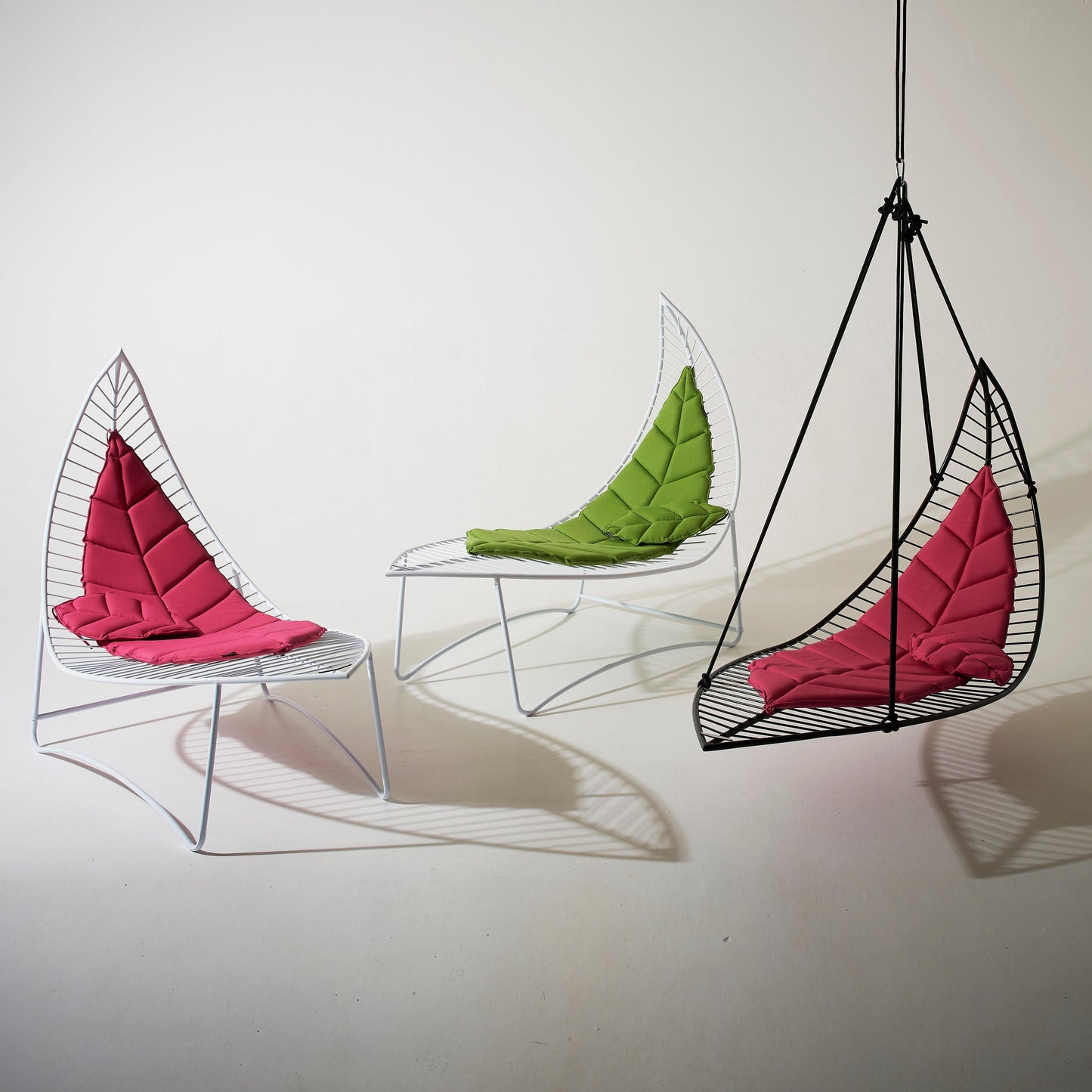 Three modern chairs with colorful cushions on a white background