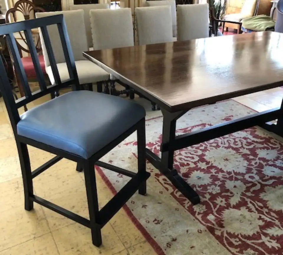 Dining table with chairs, including a blue cushioned chair, on a patterned rug.
