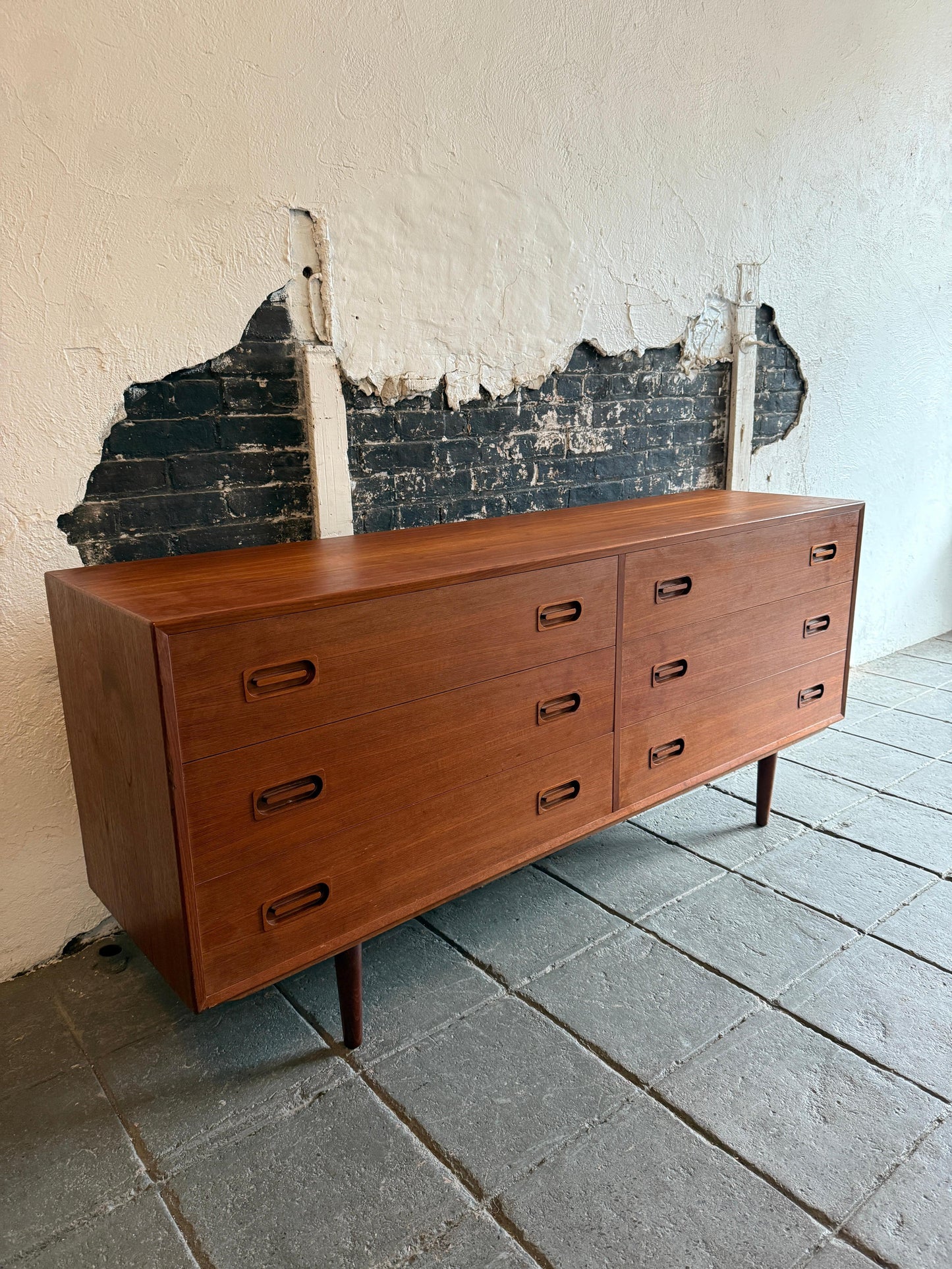 Wooden dresser against a textured wall with peeling paint