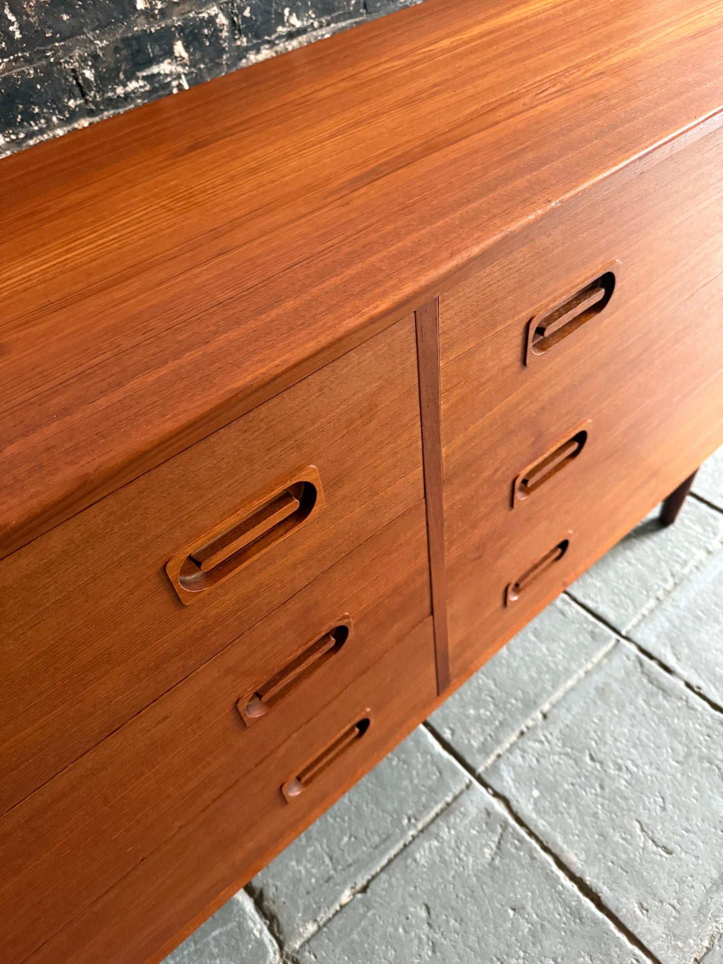 Wooden dresser with multiple drawers on a concrete floor