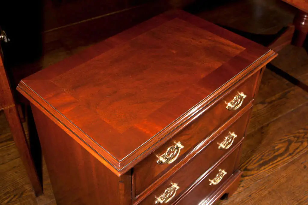 Wooden desk with leather top and gold handles on a wooden floor