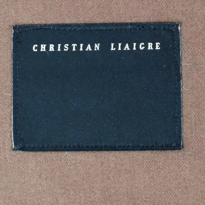 Navy label with 'Christian Liaigre' text on a beige fabric background
