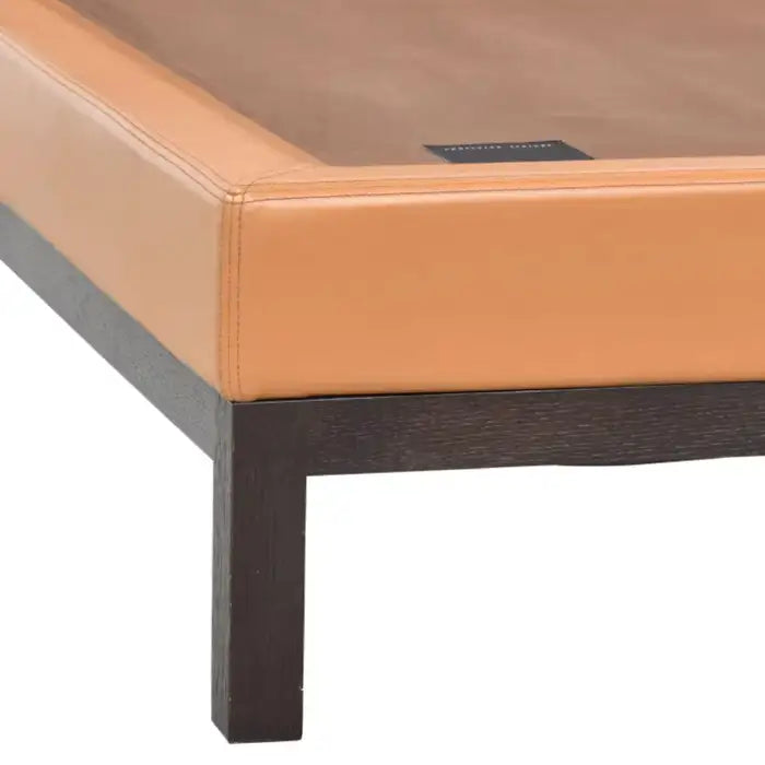 Close-up of a bed with brown leather headboard and dark wooden frame on a white background