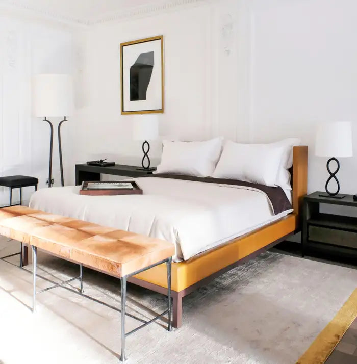 Modern bedroom with a bed, bench, and decor items.