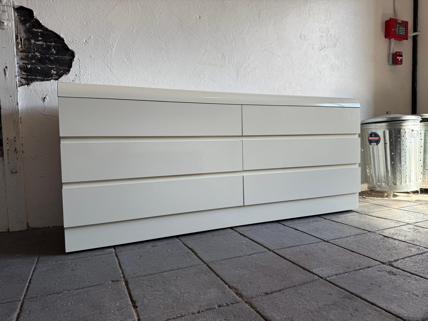 White dresser against a white wall on a tiled floor