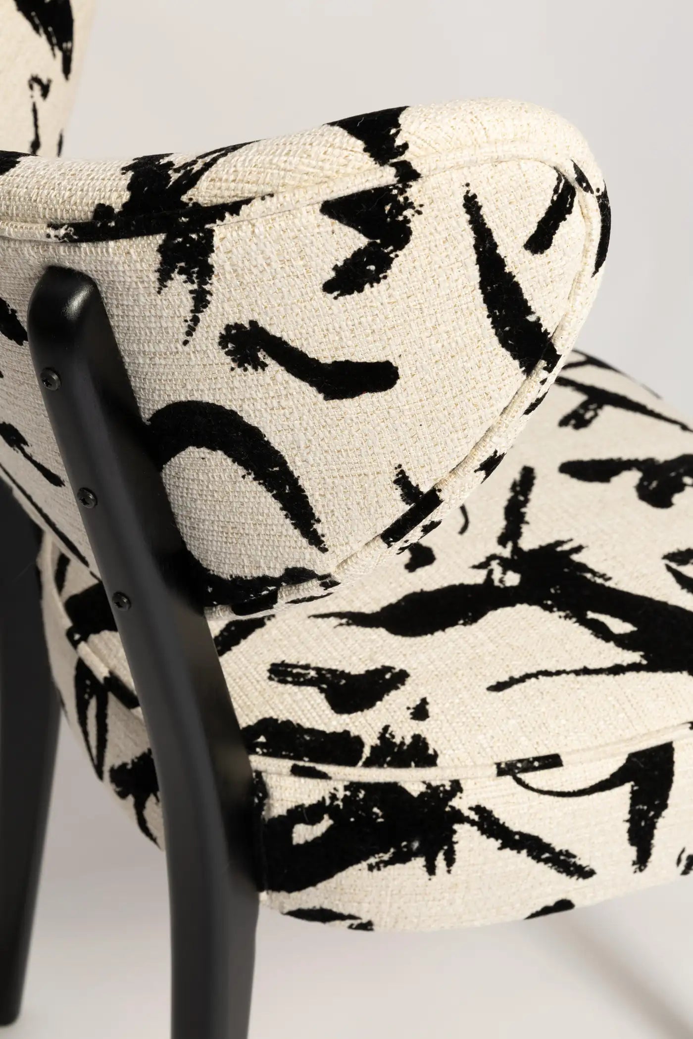 Chair with black abstract pattern on beige fabric against a light gray background