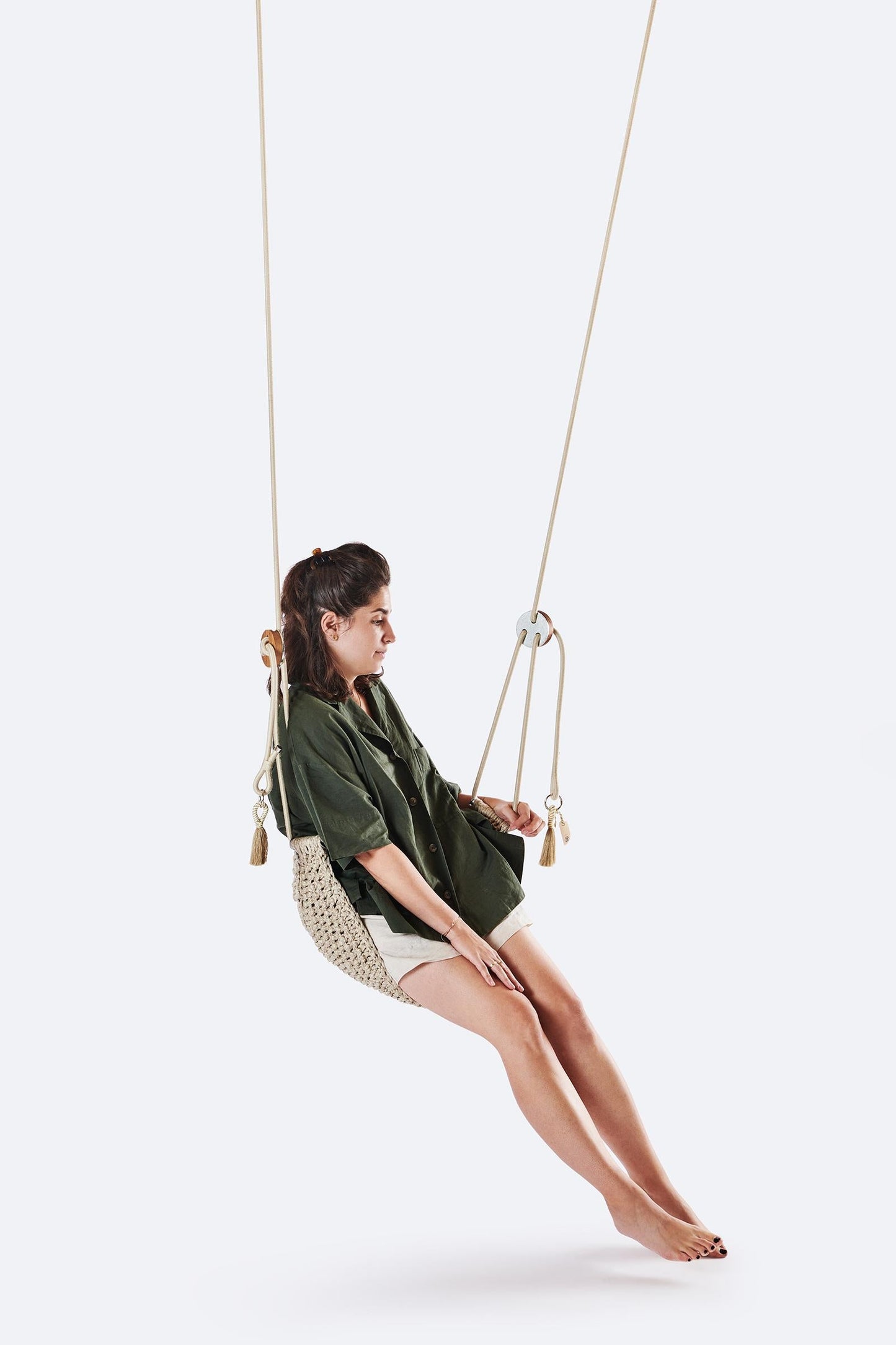 Woman sitting on a swing against a white background