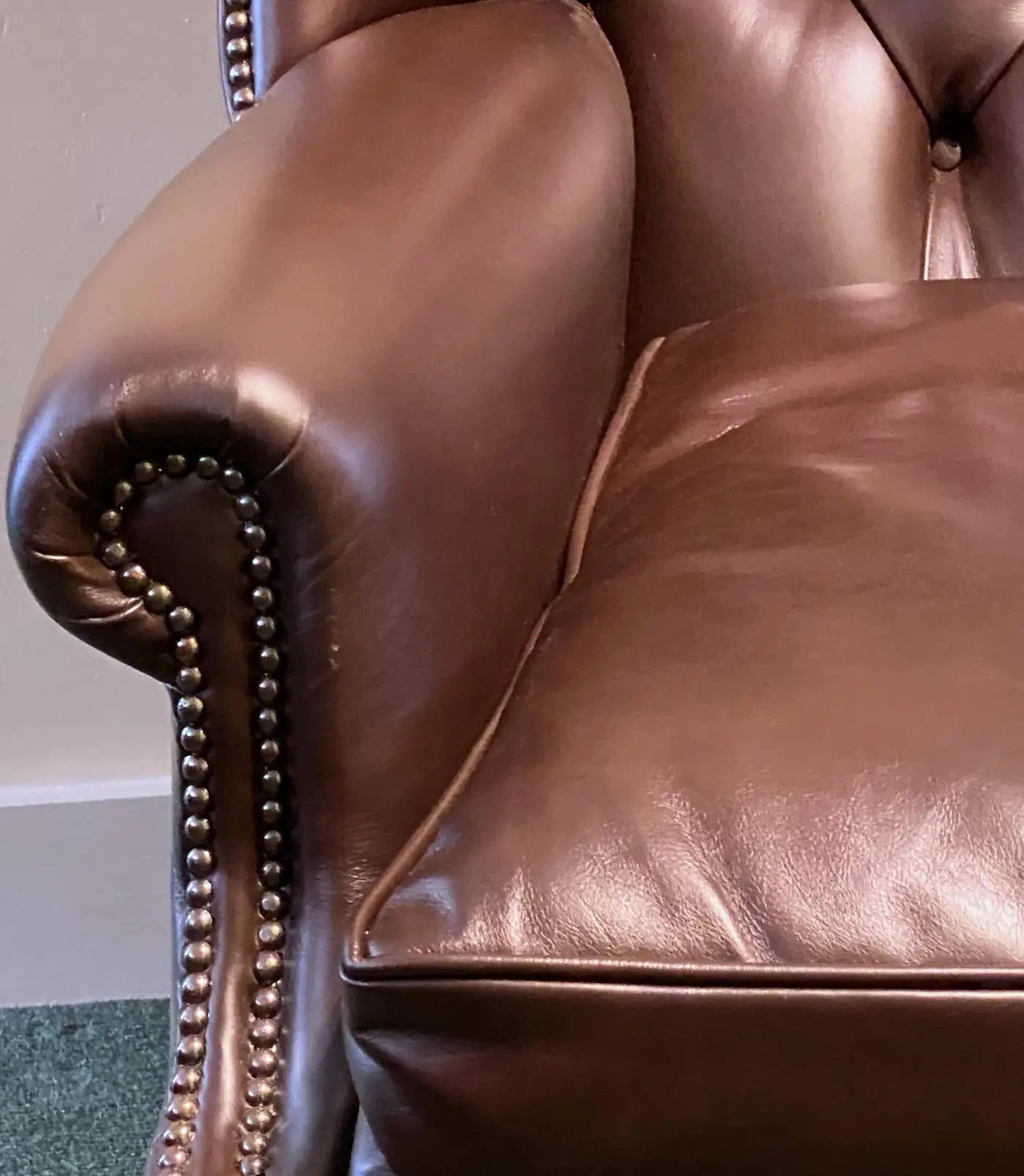 Close-up of a brown leather armchair with visible stitching details.