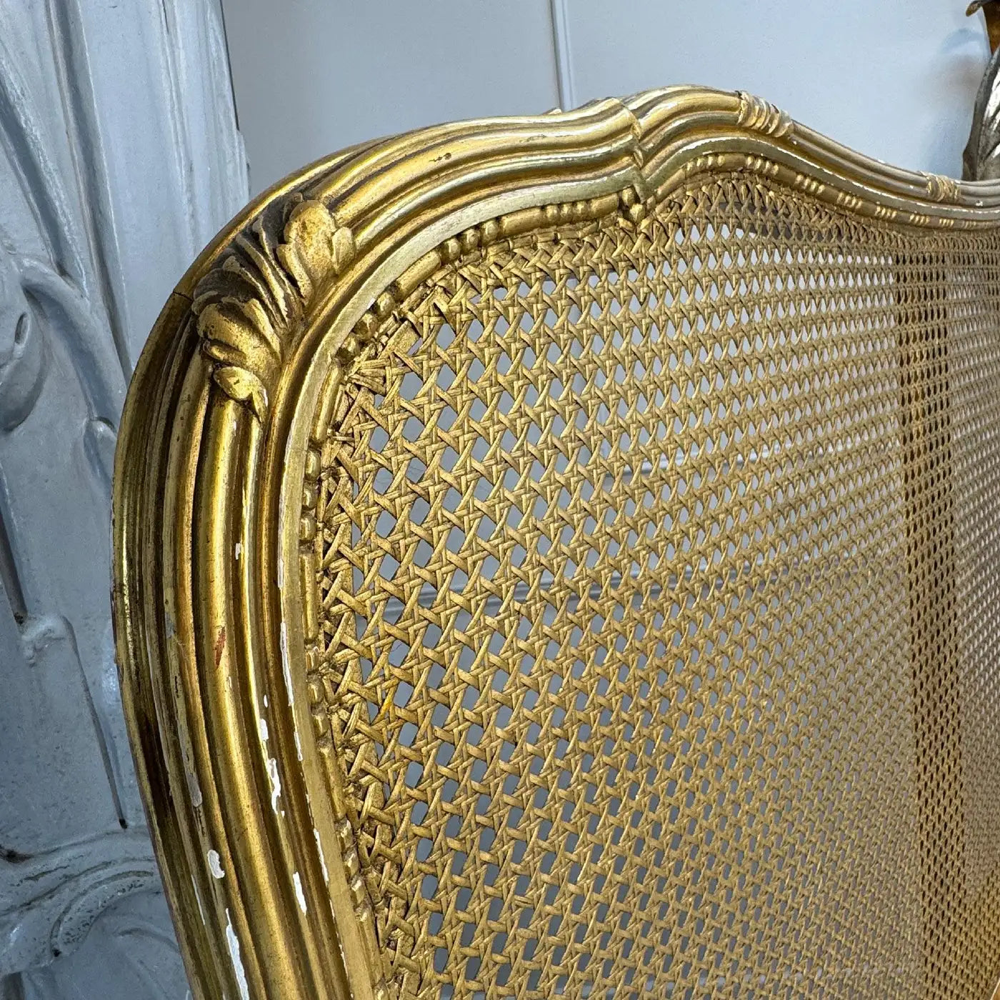 Gold-framed mirror with intricate lattice design on a white background