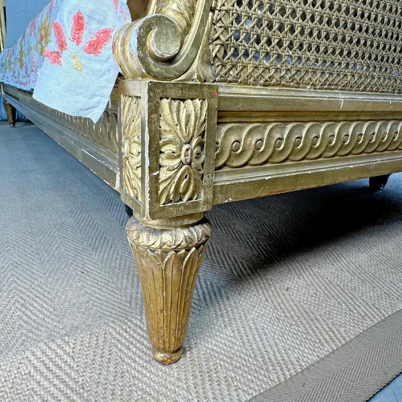 Decorative gold bed frame with intricate carvings on a textured floor.
