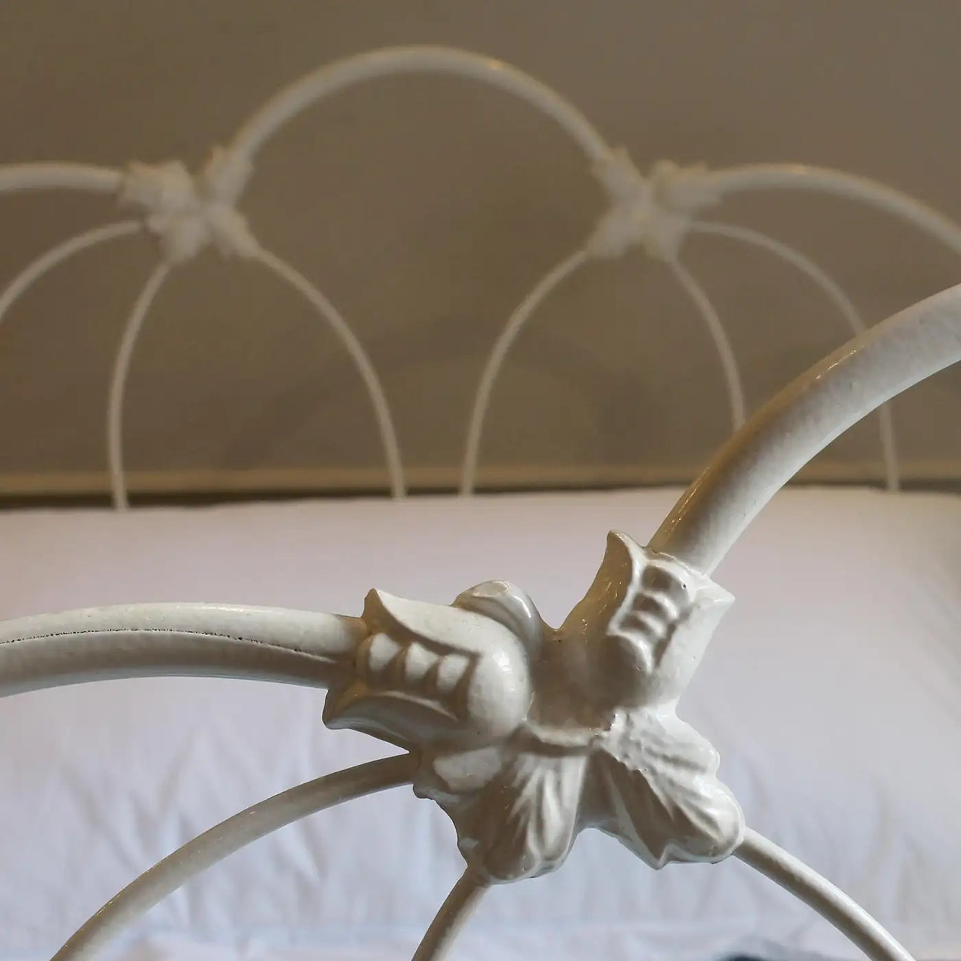Close-up of a decorative white metal headboard with intricate design.