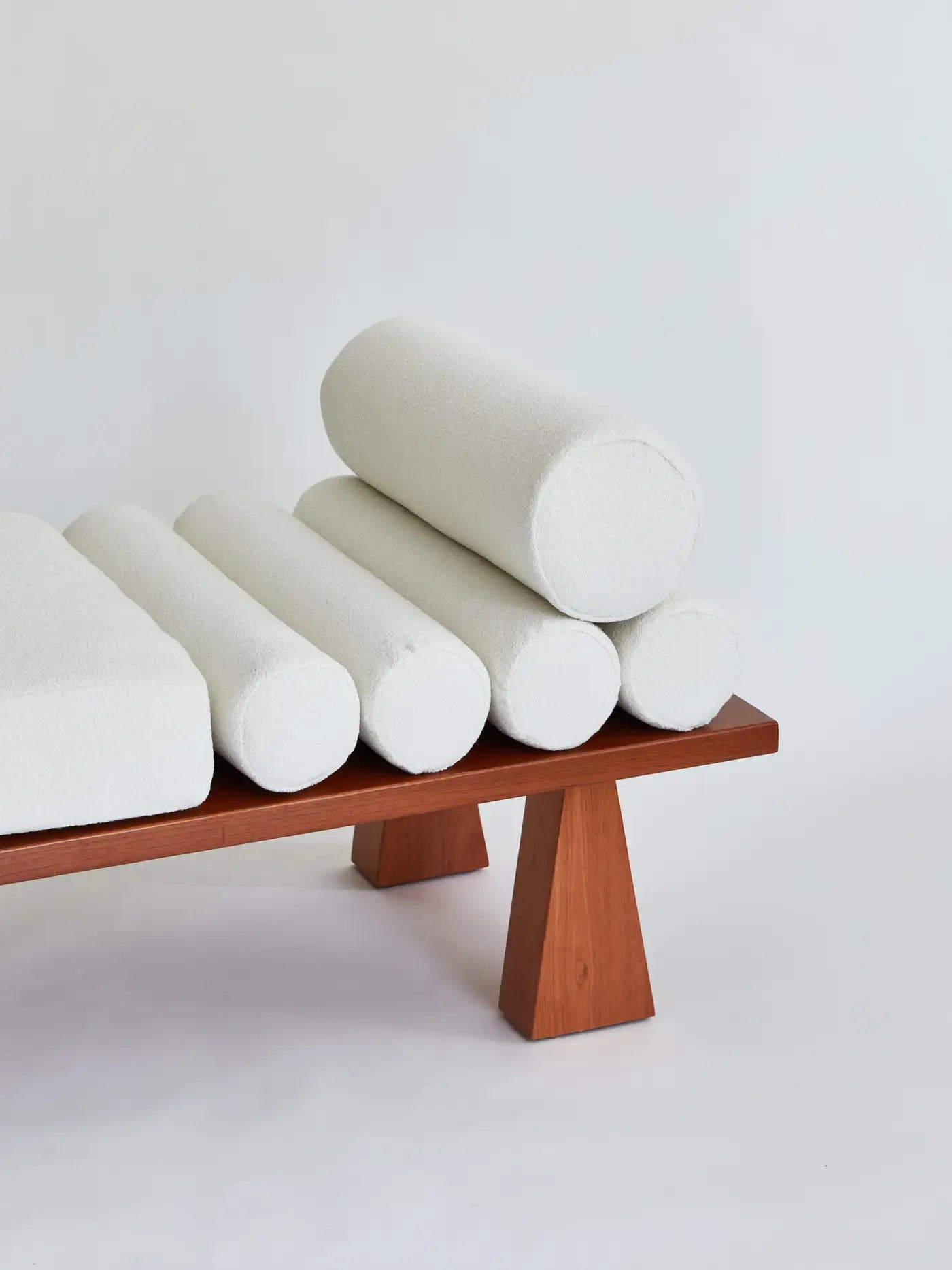 Modern chair with cylindrical white cushions on a light gray background