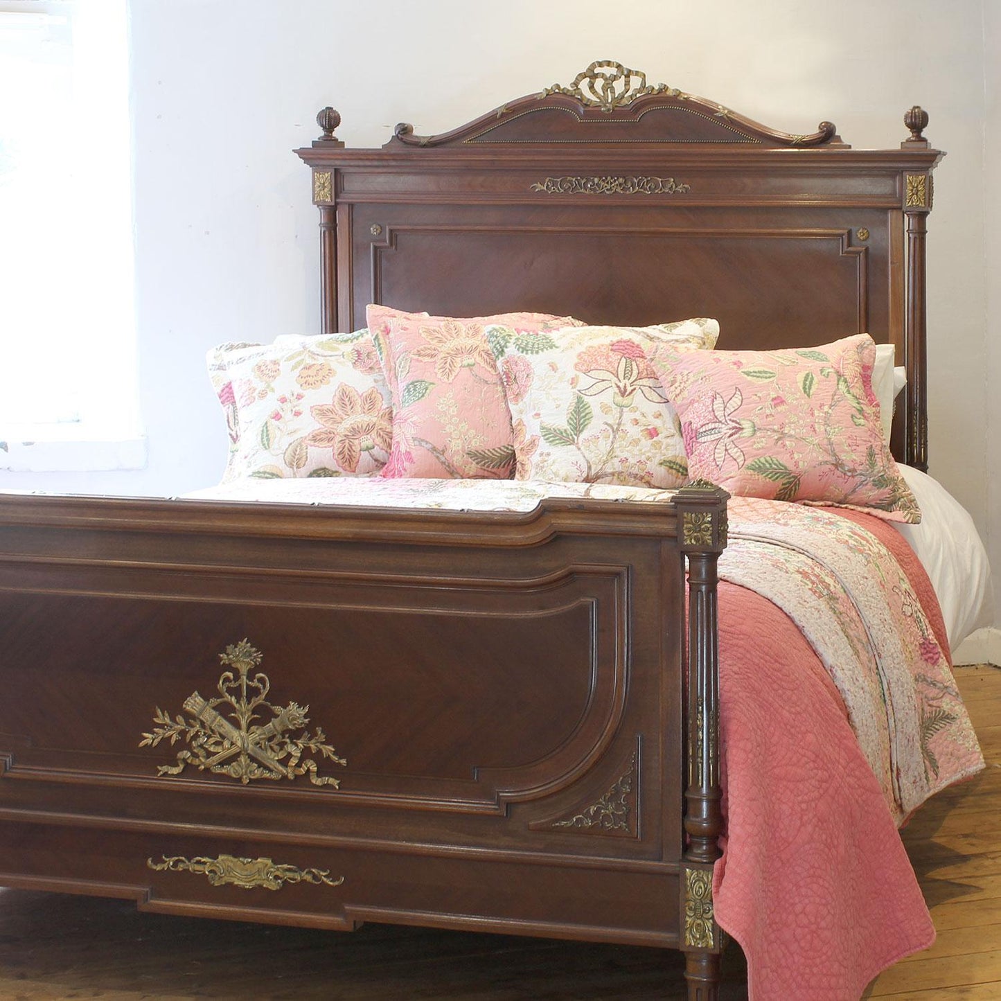 Decorative bed with floral pillows and a wooden headboard in a bedroom setting.