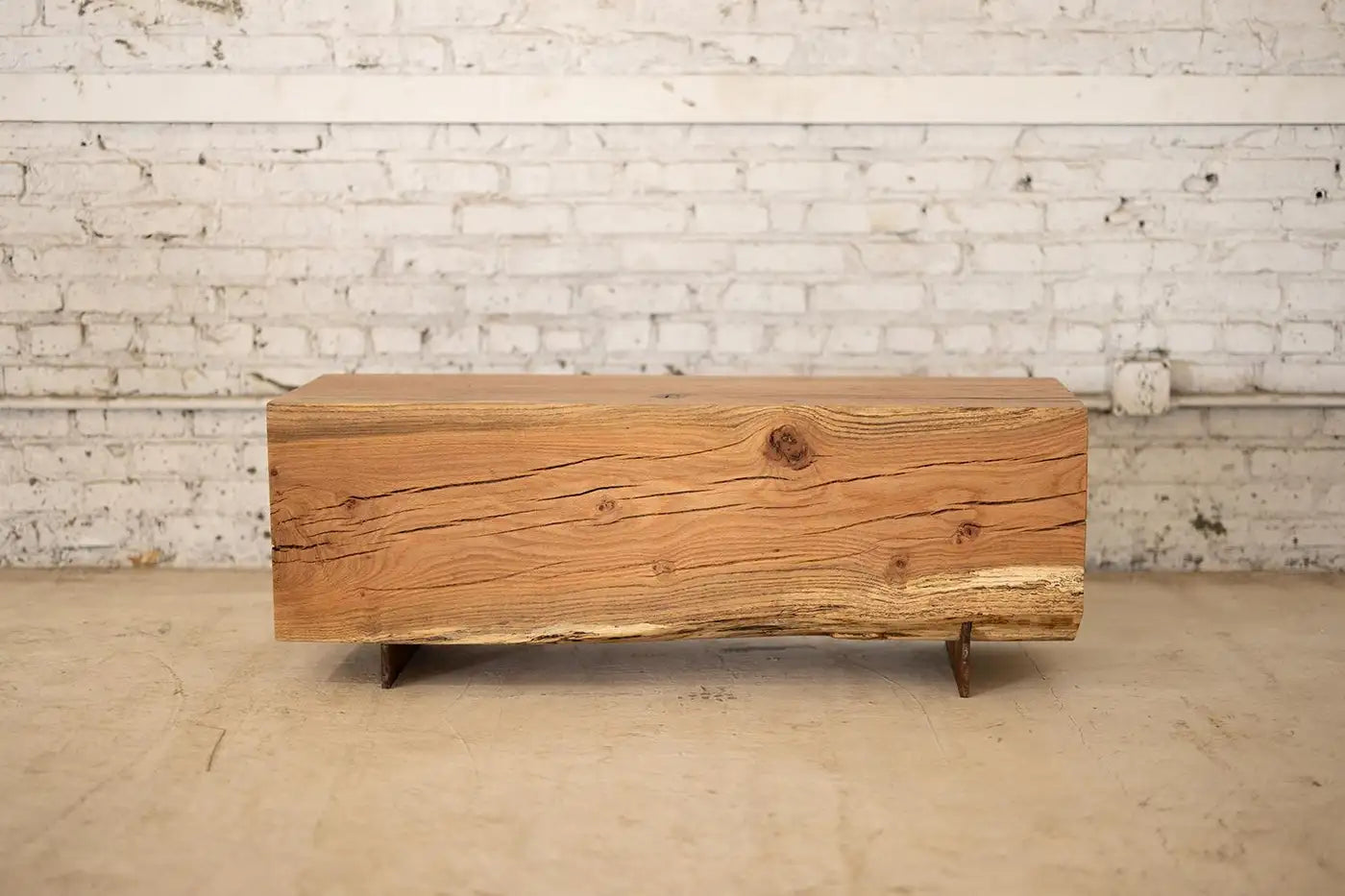 Wooden bench with a rustic design against a white brick wall.